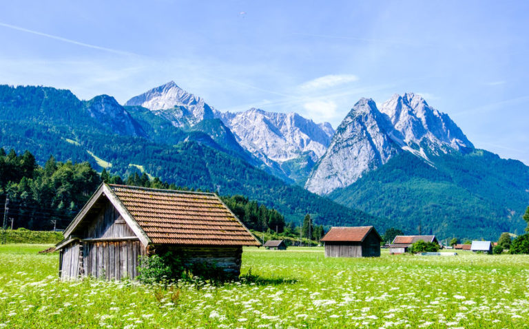 Ein Symbolbild der Höllentalangerhütte mit Waxenstein Alpspitze und Zugspitze im Hintergrund