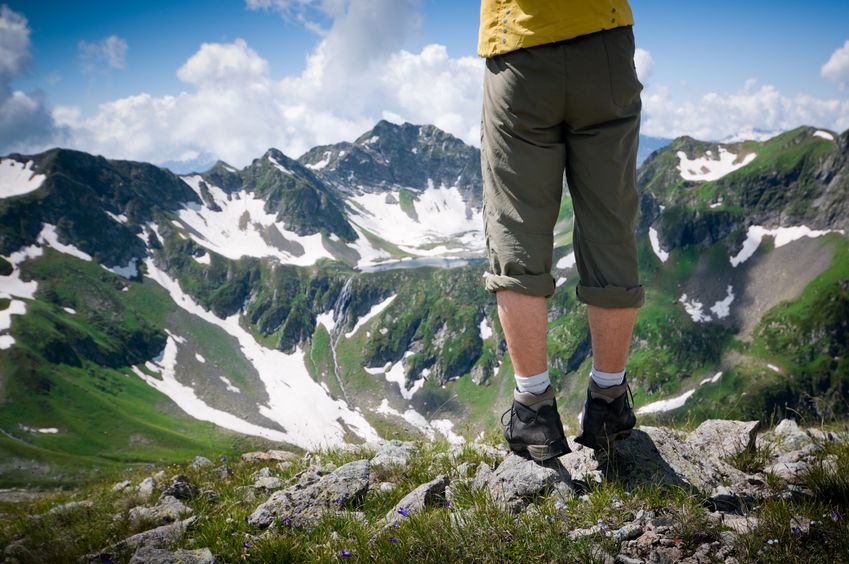 Ein Wanderer mit Wanderschuhen und Blick auf eine Bergkette